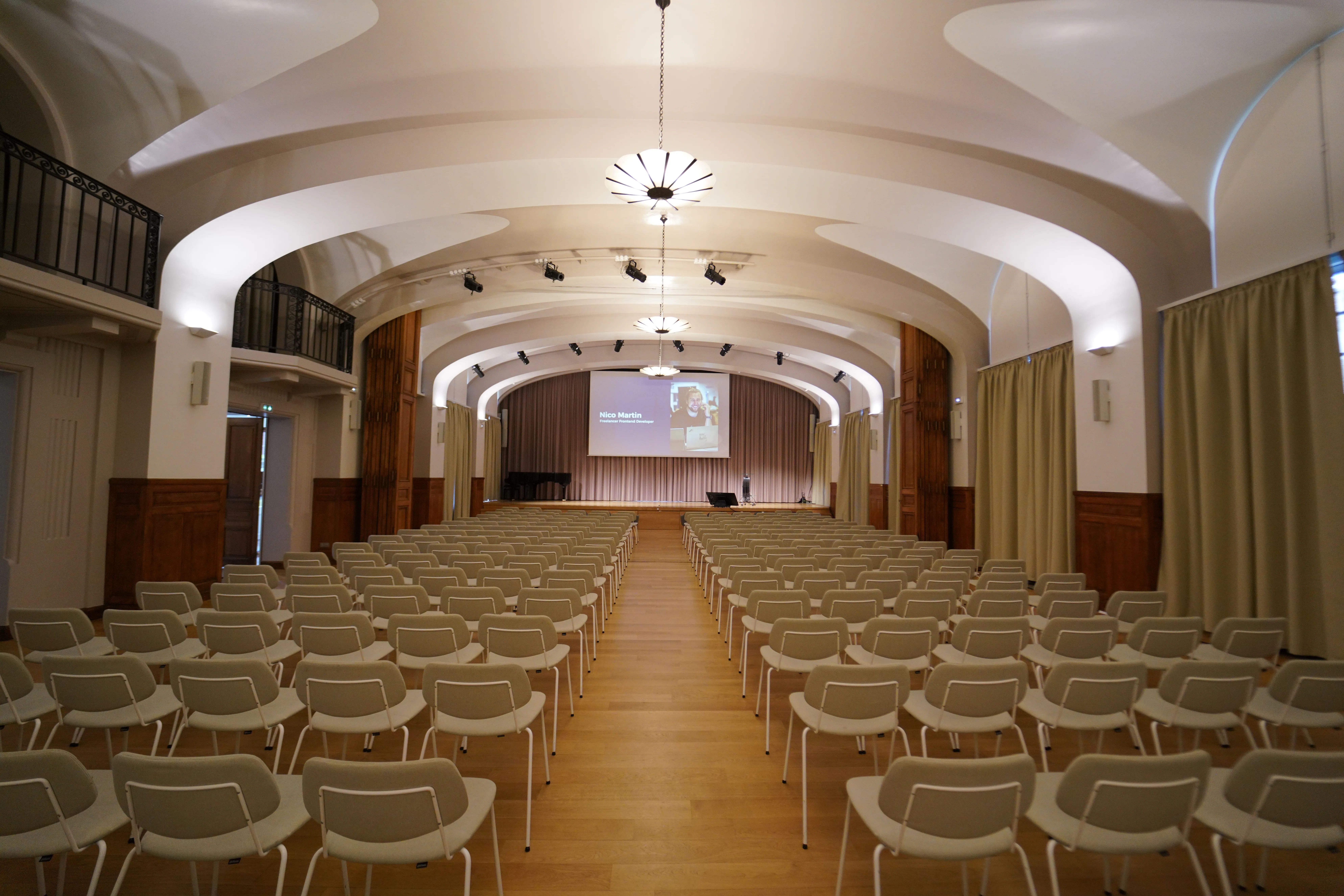 Photographie de la salle de conférence de React Paris. Le décor est luxueux mêlant moulures en bois et tons beiges pour la décoration